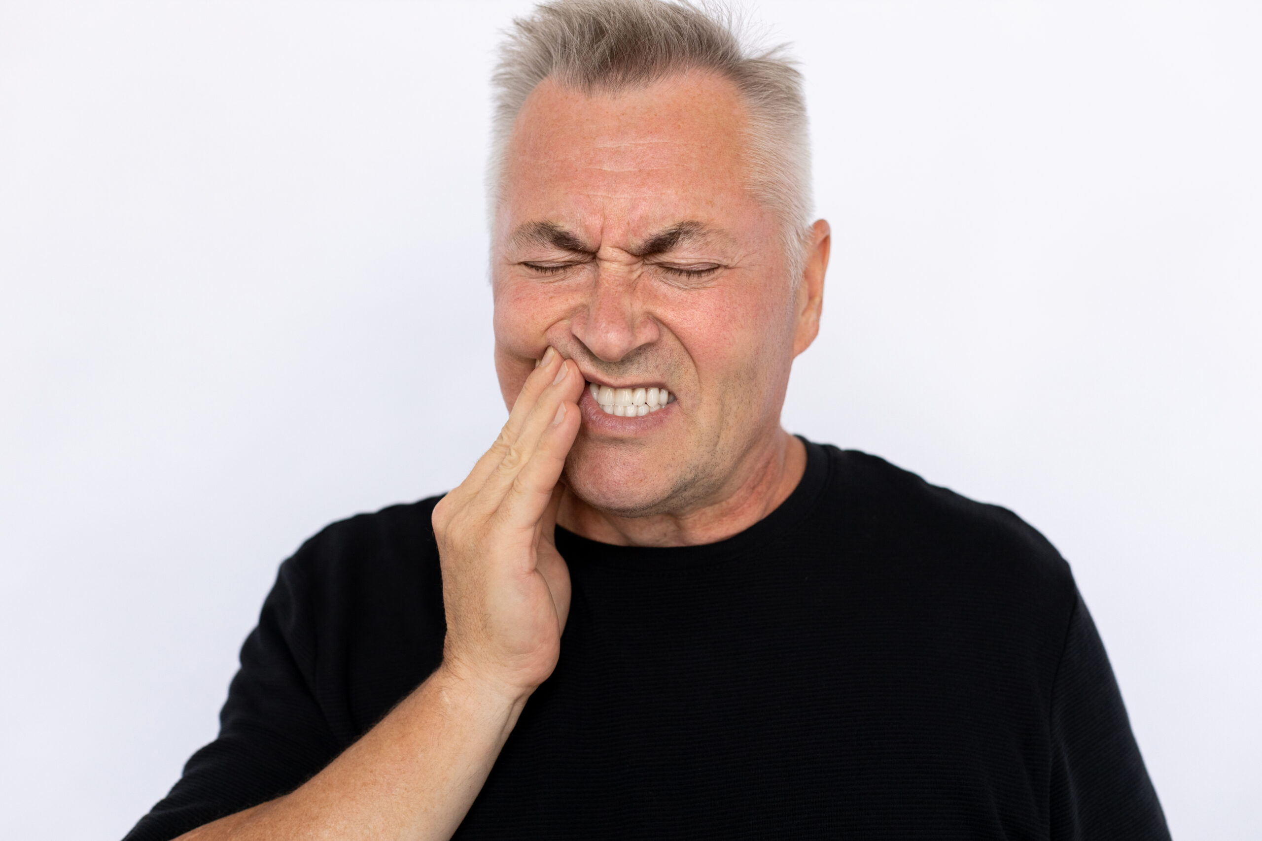 A man holding his jaw from tooth pain.