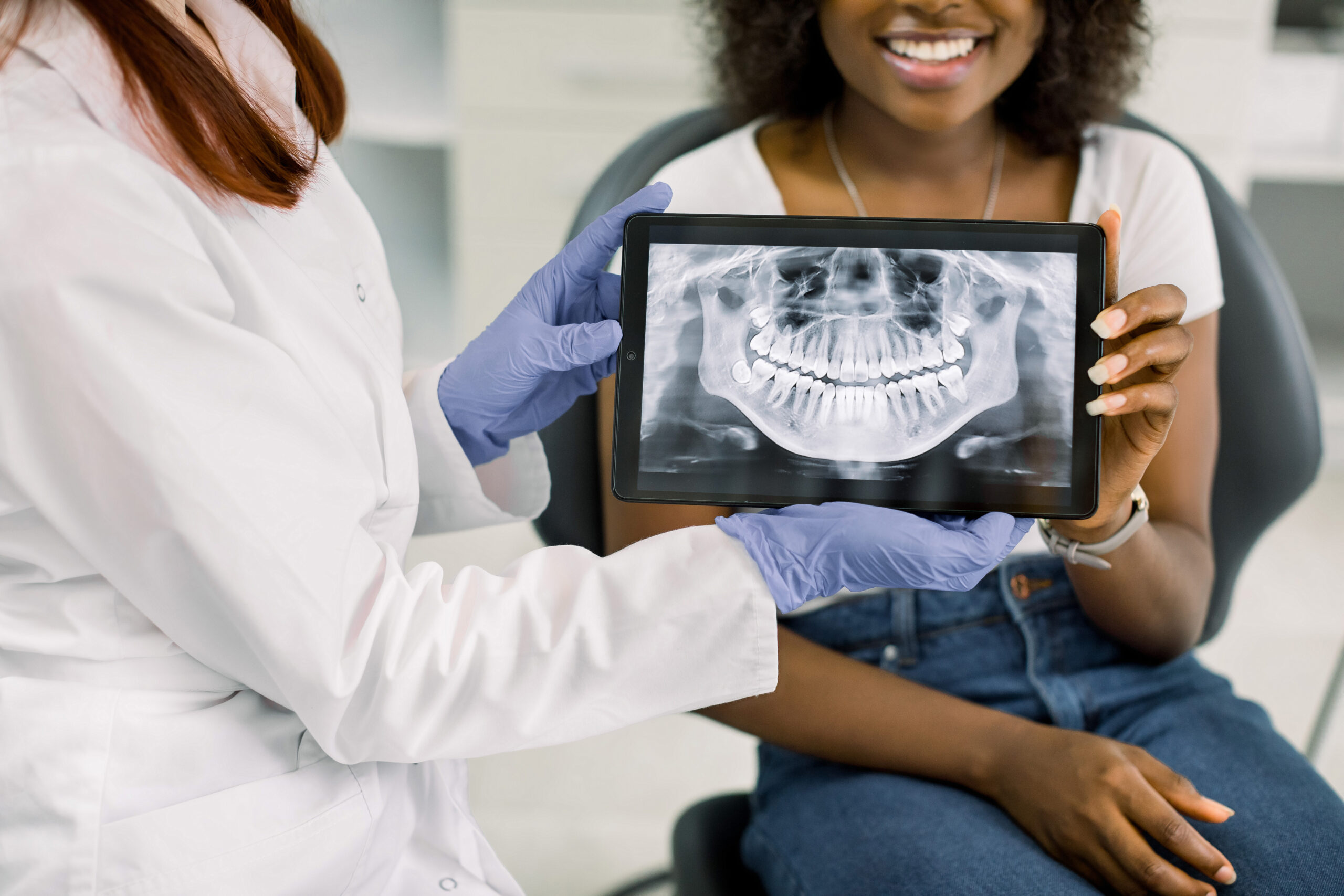 Dentist showing electronic health records of teeth x-ray to patient.