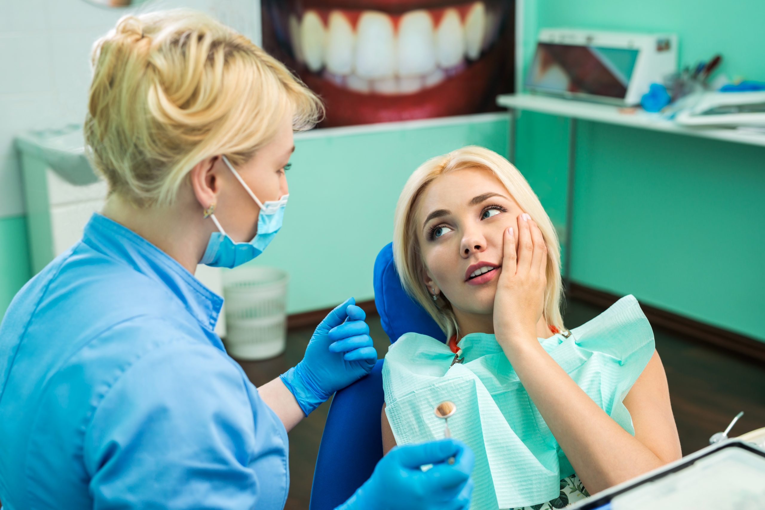 Young woman at the dentist, complaining about a dental issue.